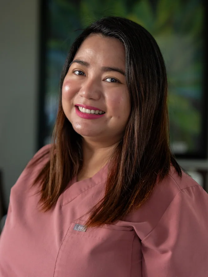 Smiling caregiver in rose scrubs providing compassionate care